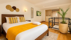 A modern hotel room with a large bed, a wooden headboard, a yellow throw blanket, and a potted plant. - Amaryllis Residences Mount Pleasant (Blantyre)