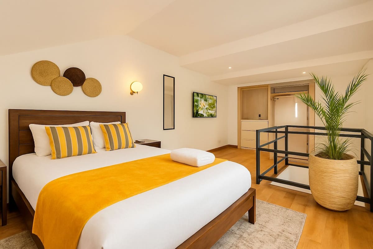 Ein modernes Hotelzimmer mit einem großen Bett, einem Holzkopfstück, einer gelben Tagesdecke und einem Blumentopf.