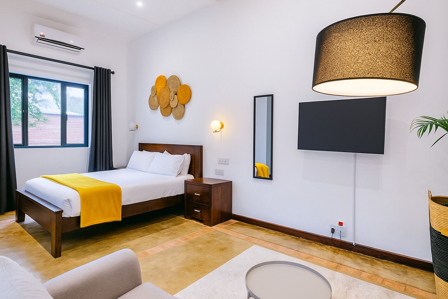 A modern hotel room with a bed, bedside table, lamp, and a large mirror.