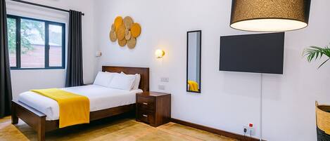 A modern hotel room with a bed, bedside table, lamp, and a large mirror.