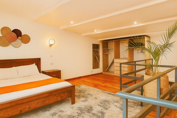 Une chambre avec un lit en bois, une table de chevet, une lampe fixée au mur, un escalier et une plante.