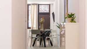 Un'area pranzo con tavolo e sedie, una porta con pannello decorativo e una pianta su un ripiano.
