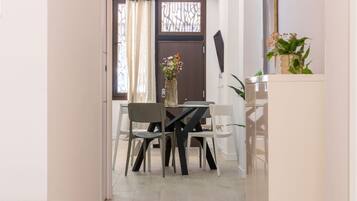 Un comedor con una mesa y sillas, una puerta con un panel decorativo y una planta sobre una encimera.