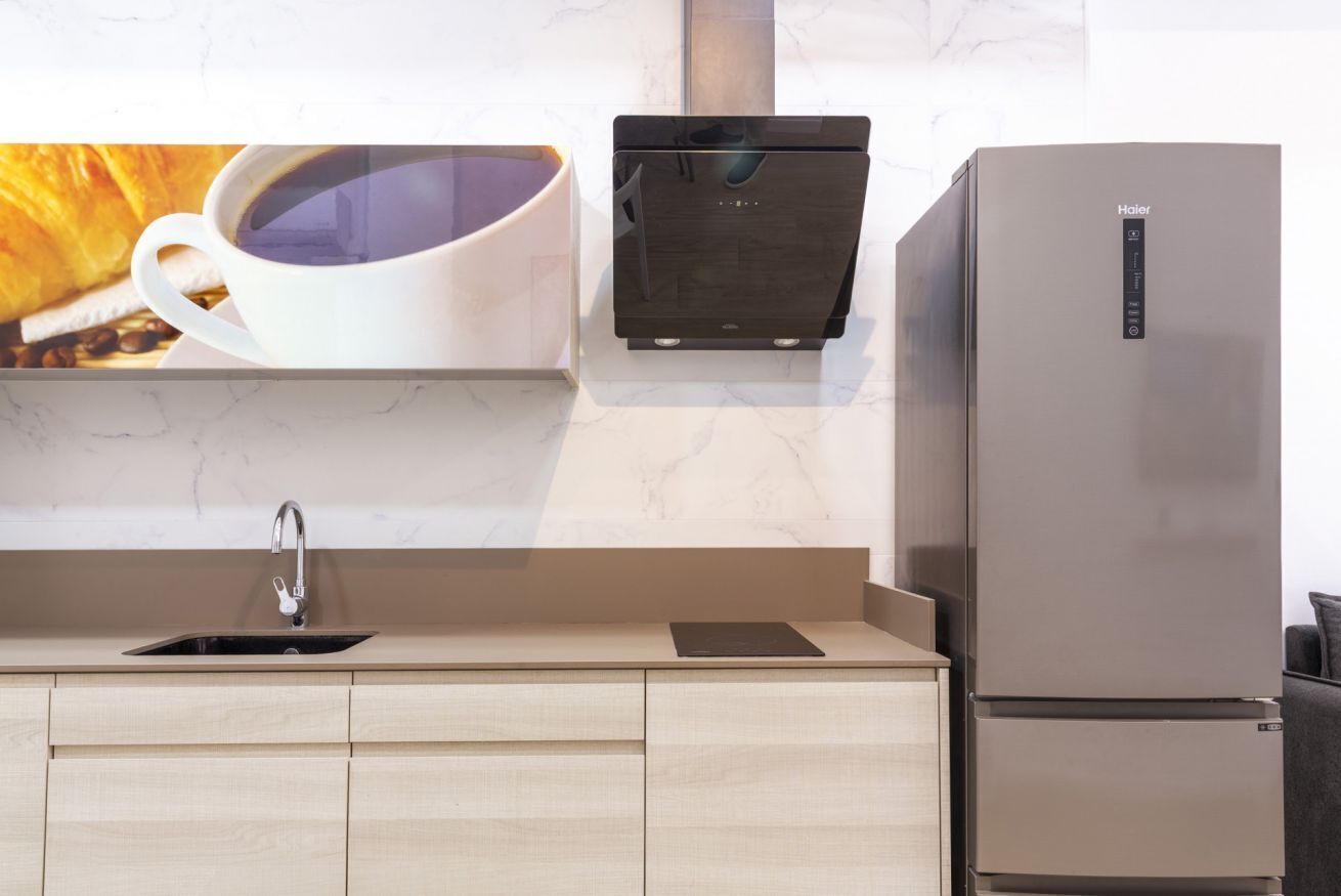 Una cocina con un refrigerador de acero inoxidable, una cafetera y un lavamanos.