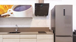 Una cucina con frigorifero in acciaio inossidabile, macchina da caffè e lavello.