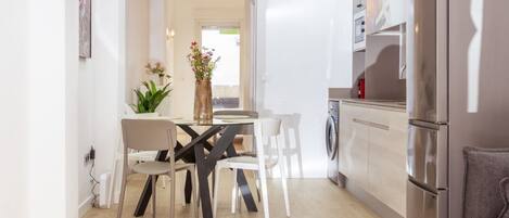 A modern kitchen with a dining area, a washing machine, and a refrigerator.