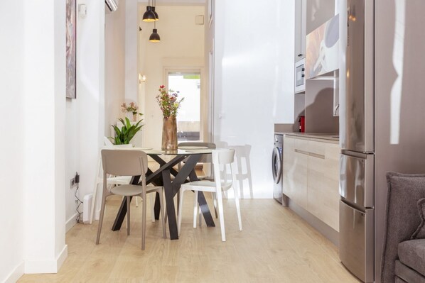 A modern kitchen with a dining area, a washing machine, and a refrigerator. - This modern apartment in Valencia combines contemporary design, comfort, and a strategic location to enjoy the city.It features a bright bedroom, a living room with a sofa bed and Smart TV, a fully equipped kitchen with state-of-the-art appliances, and a (València)