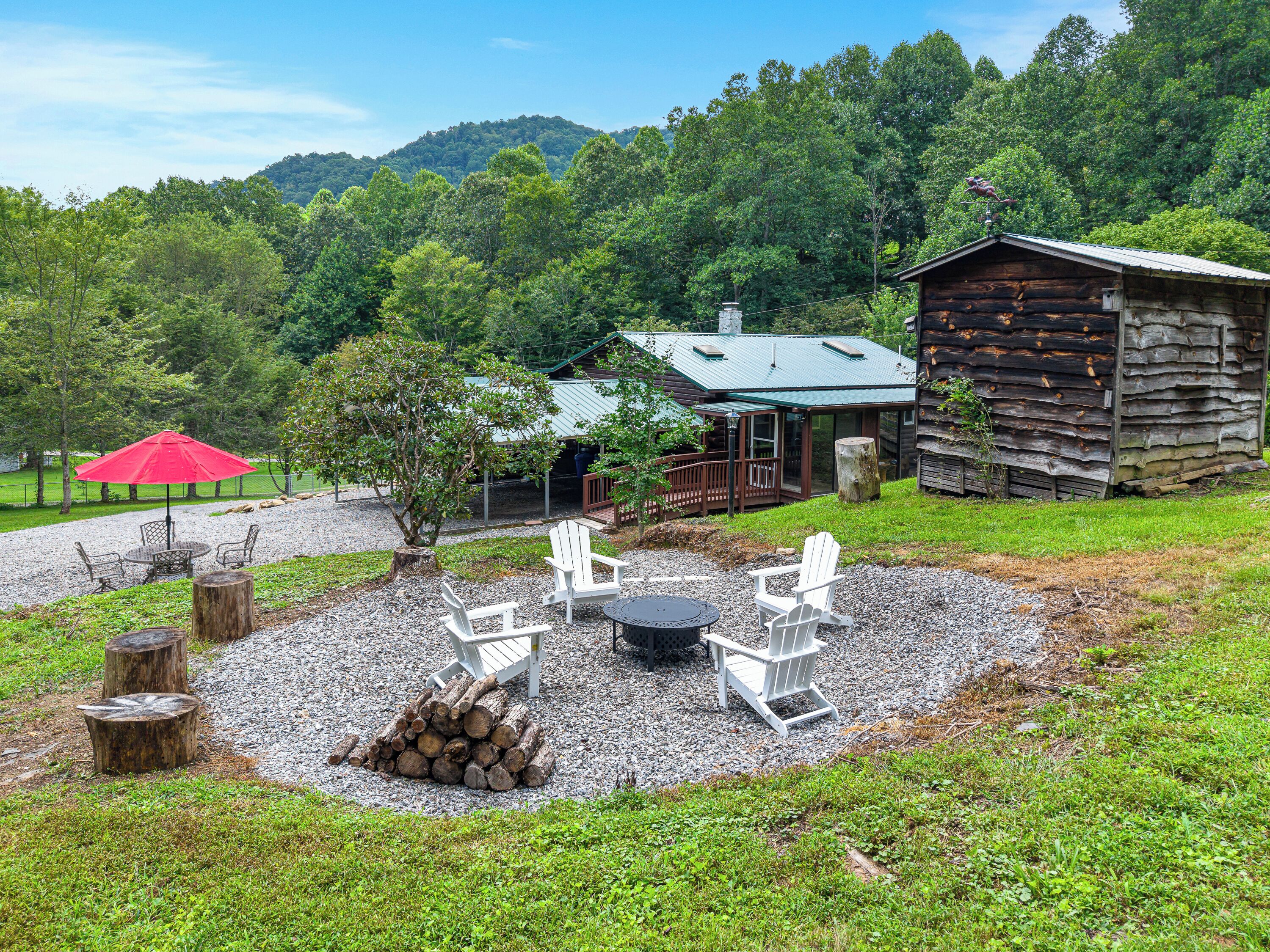 A rustic cabin with a covered patio, outdoor seating, and a fire pit.