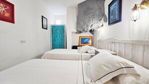 A bedroom with two beds, a decorative wall, and a framed picture. - House on the seafront (La Matanza de Acentejo)