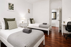 Een hotelkamer met twee eenpersoonsbedden, een bureau en een stoel.