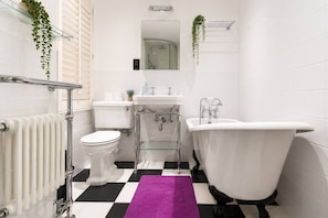 Een badkamer met een witte badkuip, een toilet, een wastafel en een radiator.