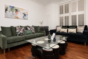 A living room with two sofas, a glass coffee table, and a painting on the wall.