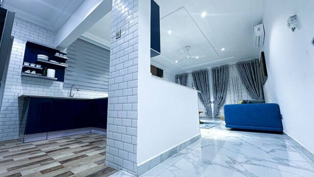 Een moderne keuken met witte bakstenen muren, een marmeren vloer en een blauwe bank in de woonkamer.