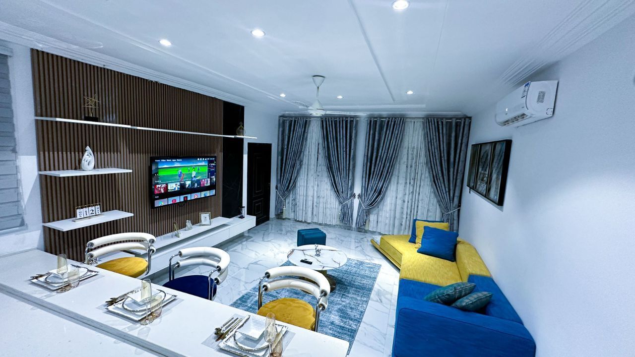 Een moderne woonkamer met een televisie, bank en eethoek.