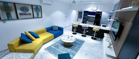 A modern living room with a yellow sofa, blue armchair, and a coffee table.