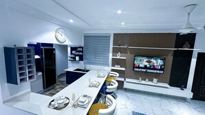 Een moderne keuken met een centraal eiland, inbouwplanken en een flatscreen televisie.