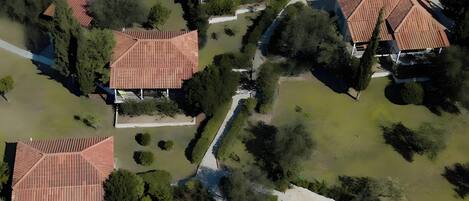 Vista aérea de una zona residencial con varias casas, un camino central y abundante vegetación.