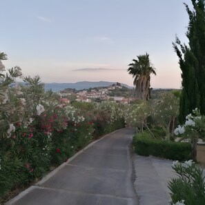 A paved road with a view of a town and mountains in the distance.