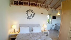 A bedroom with a bed, two bedside tables with lamps, a wall decoration, a television, and a wardrobe. - Country House 'No 3 Holiday Home' with Sea View, Wi-Fi, and Air Conditioning (Methoni)