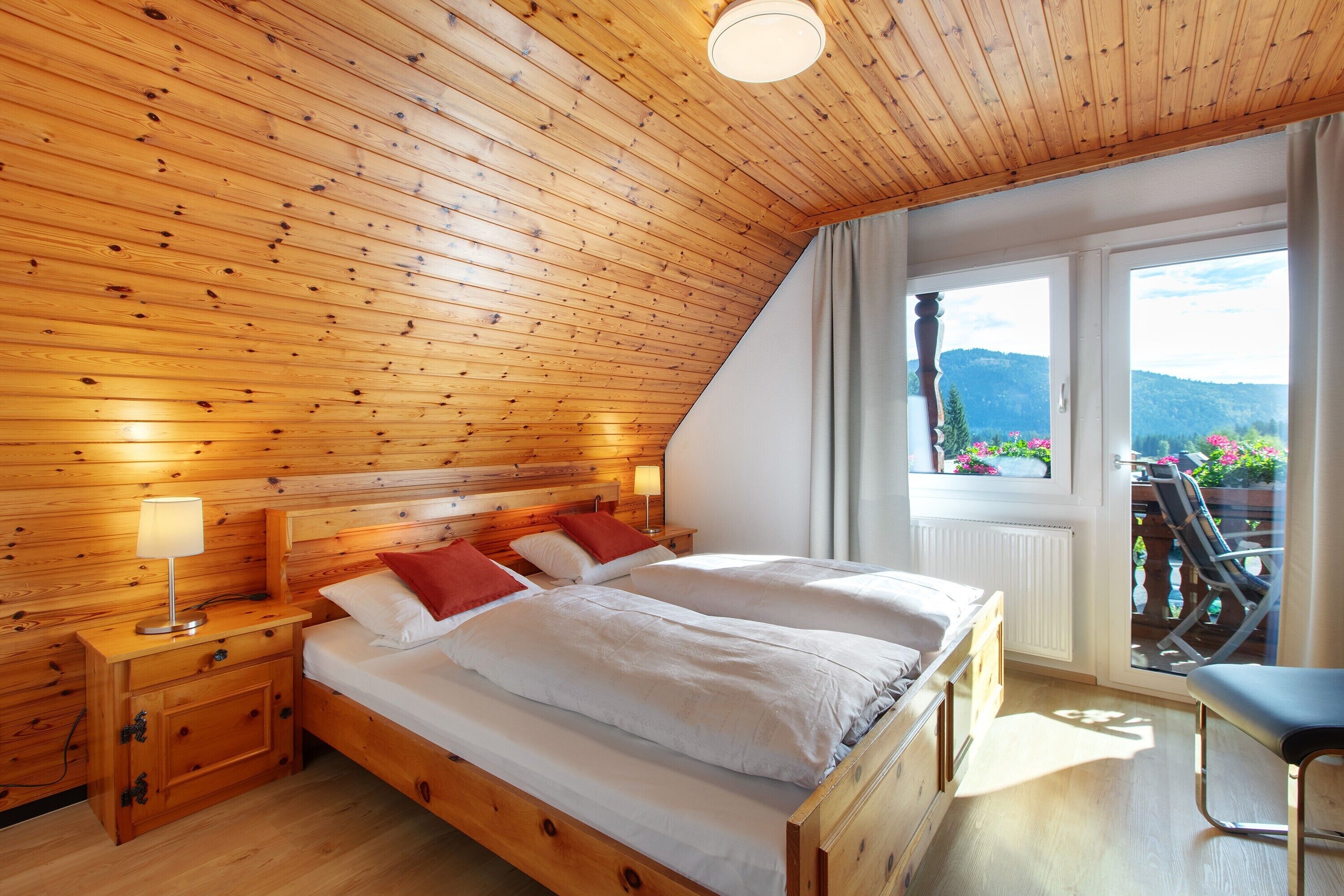 Ein Zimmer mit Holzwänden, einem Bett, Nachttischen und einem Fenster mit Blick.
