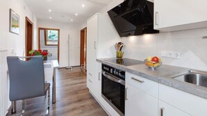 A modern kitchen with white cabinets, a stainless steel sink, and a built-in oven.