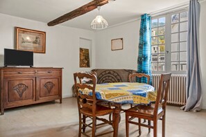 Un comedor con una mesa, sillas, un armario de madera, un televisor y obras de arte en las paredes.