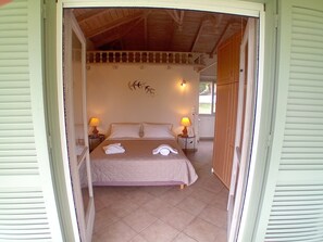 A room with a bed, two bedside lamps, a wall decoration, and a door leading outside.
