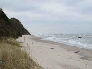 A beach with sand, grass, and waves.