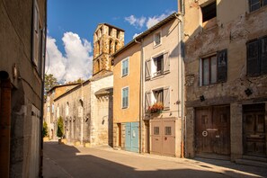 Una calle estrecha con edificios históricos, una torre de iglesia y un letrero que indica un área de estacionamiento.