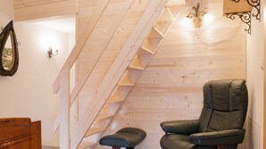 Un interior de madera con una escalera, una silla de masaje y un armario de madera.