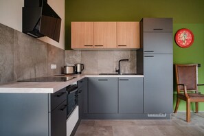 A modern kitchen with grey cabinets, a wooden countertop, a sink, and a red clock on the wall. - Apartment 'Resi' with Balcony and Wi-Fi (Achenkirch)