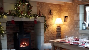 A cozy room with a fireplace, a table set for dining, and a Christmas wreath. - La Clef des Champs - Pool and Jacuzzi - Lémeré (Lémeré)