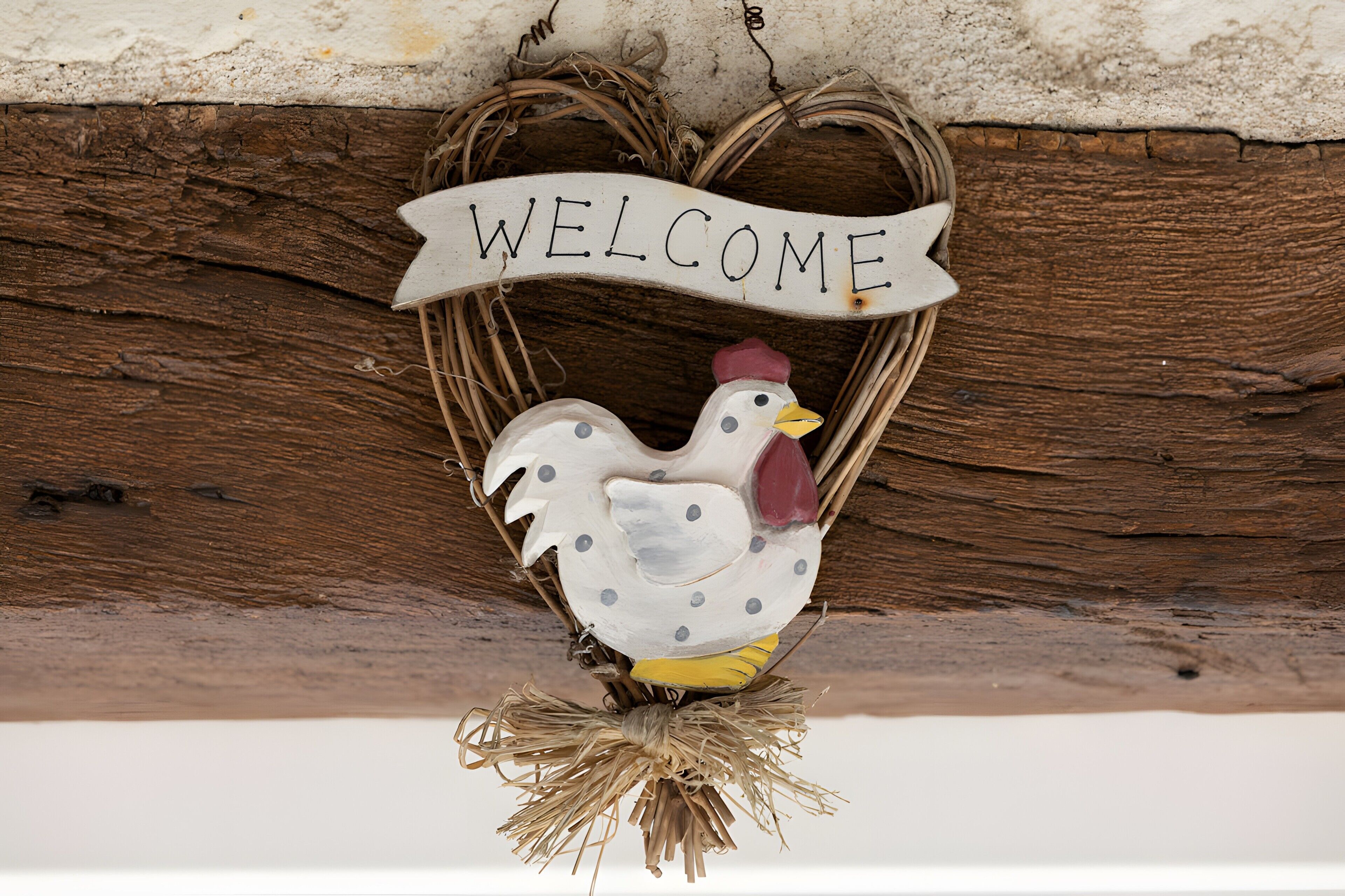 A rustic welcome sign with a chicken decoration.