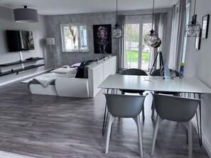 Una sala moderna con sofá, mesa de comedor, sillas y televisor.