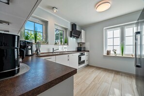 A modern kitchen with a large island, built-in appliances, and large windows.