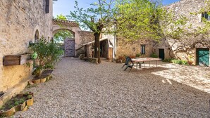 A courtyard with stone buildings, a wooden gate, and a gravel path. - Queen’s Room with Pool and Garden (Sauzet)