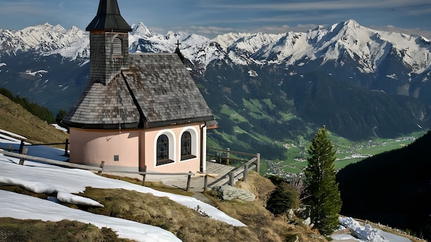 A small building with a pointed roof and a cross on top, surrounded by snow-covered mountains and a valley. - Apartment 'Mia' with Mountain View, Balcony and Wi-Fi (Ried im Zillertal)