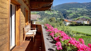 A wooden building with a balcony overlooking a green valley and mountains. - Apartment 'Mia' with Mountain View, Balcony and Wi-Fi (Ried im Zillertal)