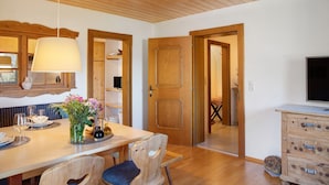 A wooden dining table with chairs, a vase with flowers, and a television on a dresser. - Apartment 'Mia' with Mountain View, Balcony and Wi-Fi (Ried im Zillertal)