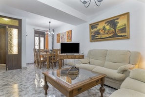Un salon comprenant un canapé, une table basse, un téléviseur et un coin repas avec des chaises et une table.