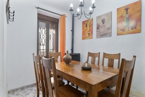 Un coin repas comprenant une table en bois, six chaises, un lustre et deux tableaux accrochés au mur.