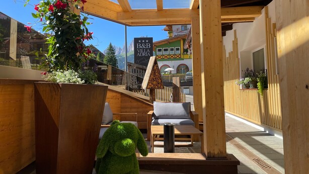 Ein Holzinterieur mit einer Sitzecke, einer großen Kübelpflanze und Blick auf einen Berg.