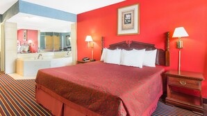 A hotel room with a large bed, a bathroom with a bathtub, and a red wall. - Hotel Inn Albany (Albany)