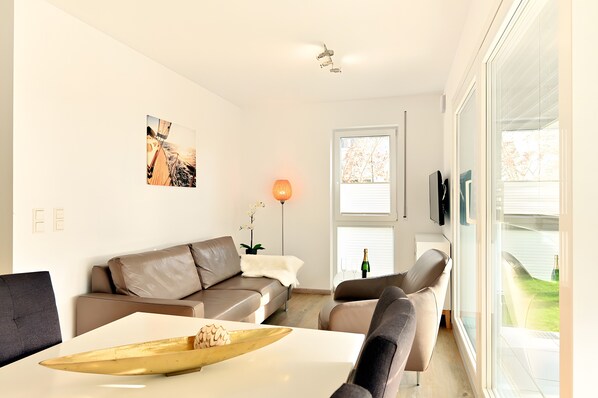 A modern living room with a sofa, armchairs, a coffee table, and a large window.