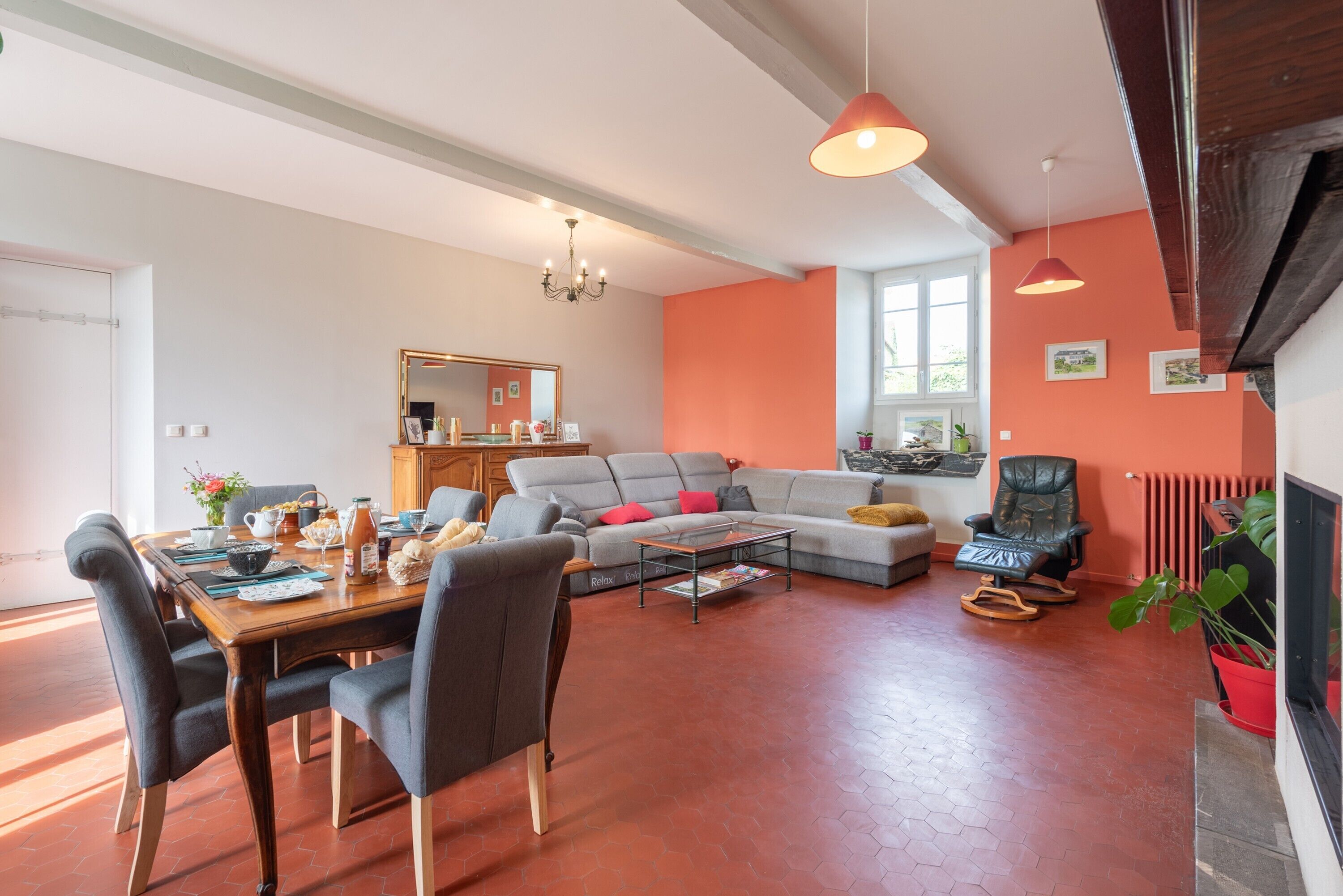 Un salon comprenant un canapé, une table à manger, des chaises, une table basse, une cheminée et une grande fenêtre.