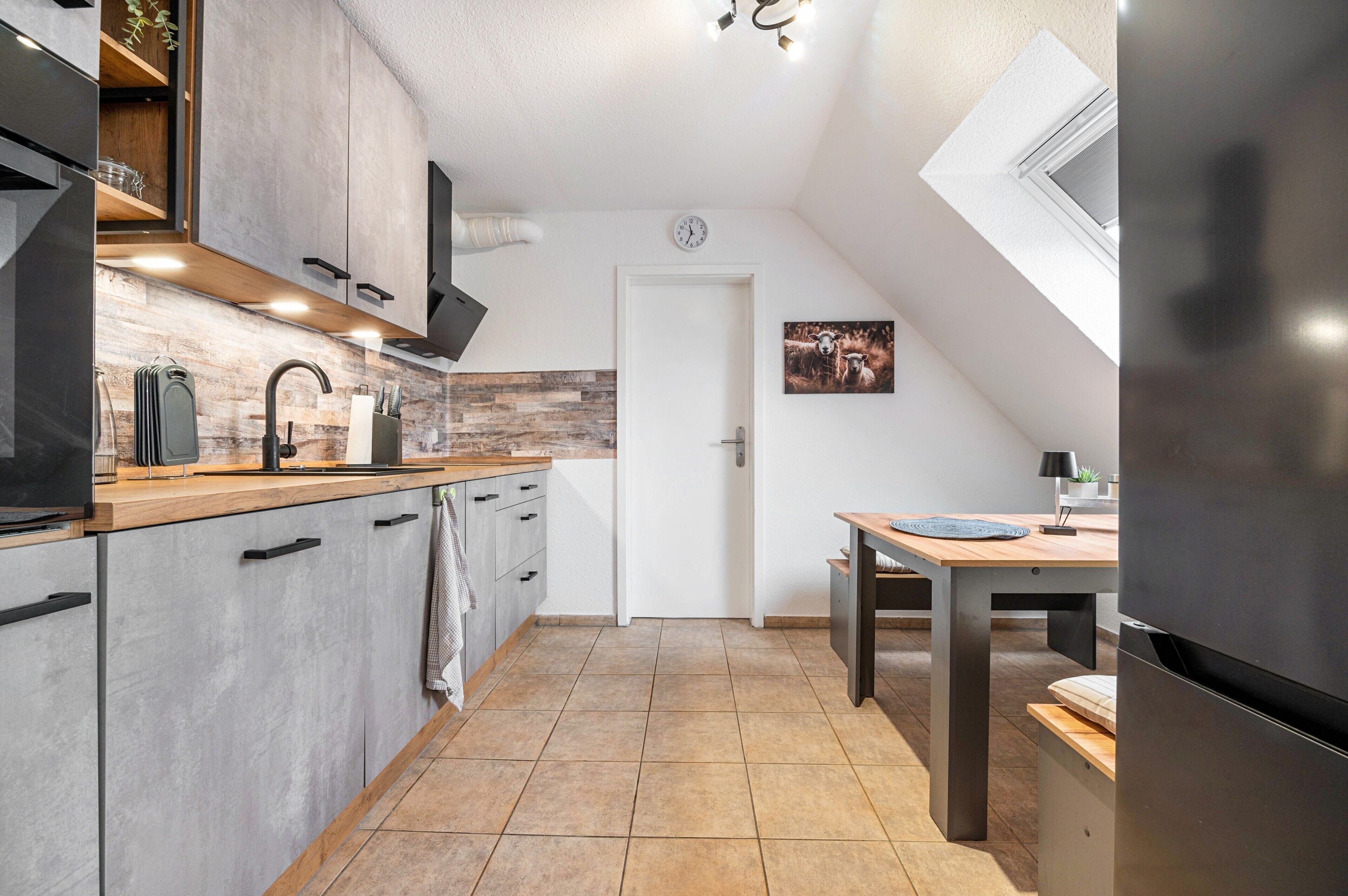 Een moderne keuken met een inbouwoven, een spoelbak en een eethoek met een tafel en stoelen.