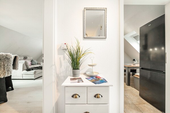 Una cocina moderna con encimera blanca, un refrigerador negro y una zona de comedor con una mesa y sillas.