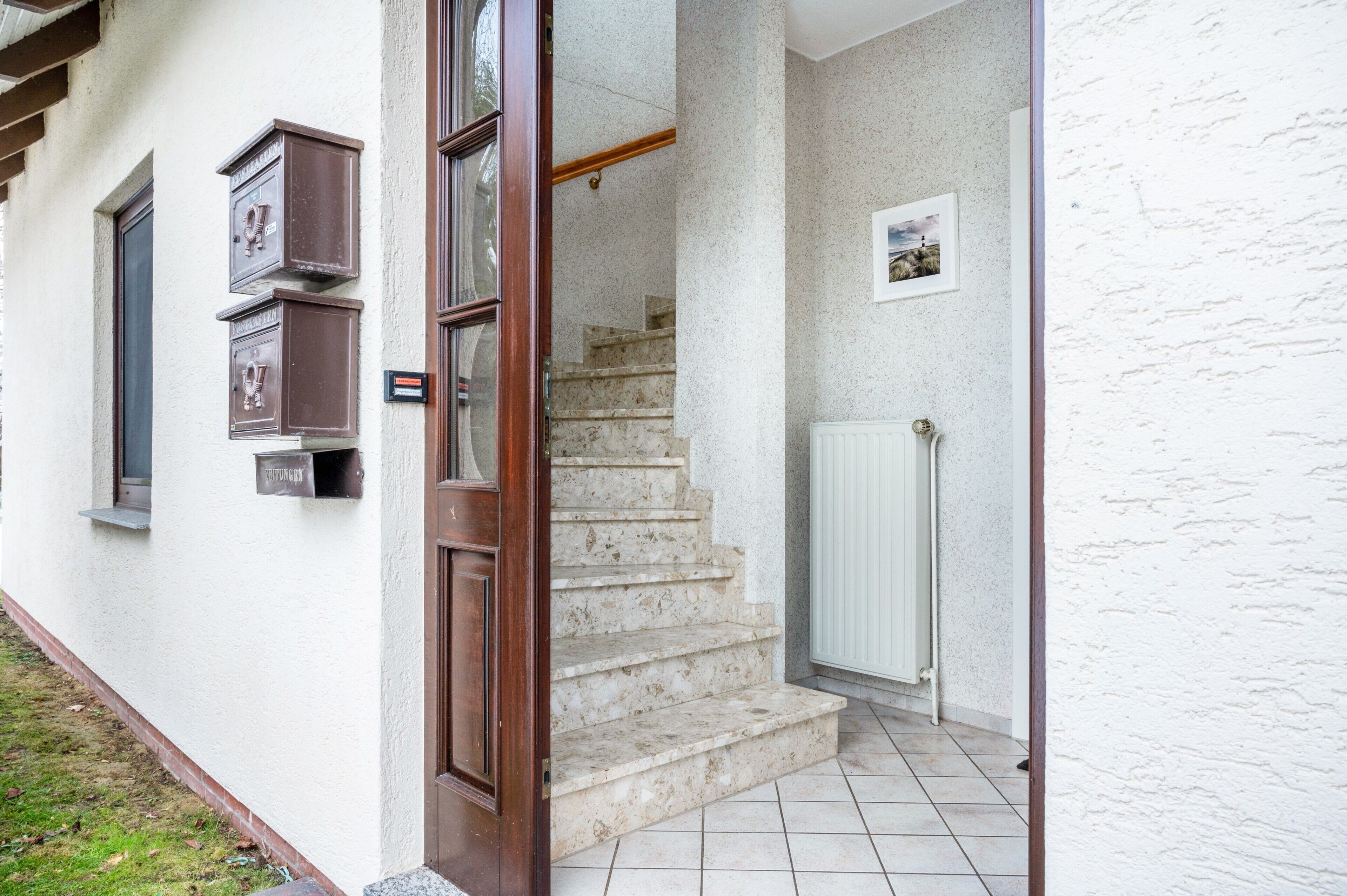 A staircase leading to a door, a mailbox, and a radiator.