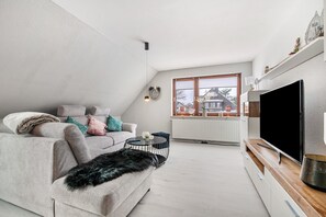 Un salon moderne avec un canapé, une table basse et un téléviseur.