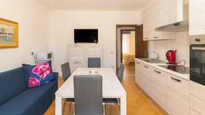 Un espai habitable pràctic amb zona de menjador, petita cuina i televisió.